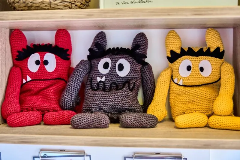 Drie gehaakte knuffelmonsters op een plank